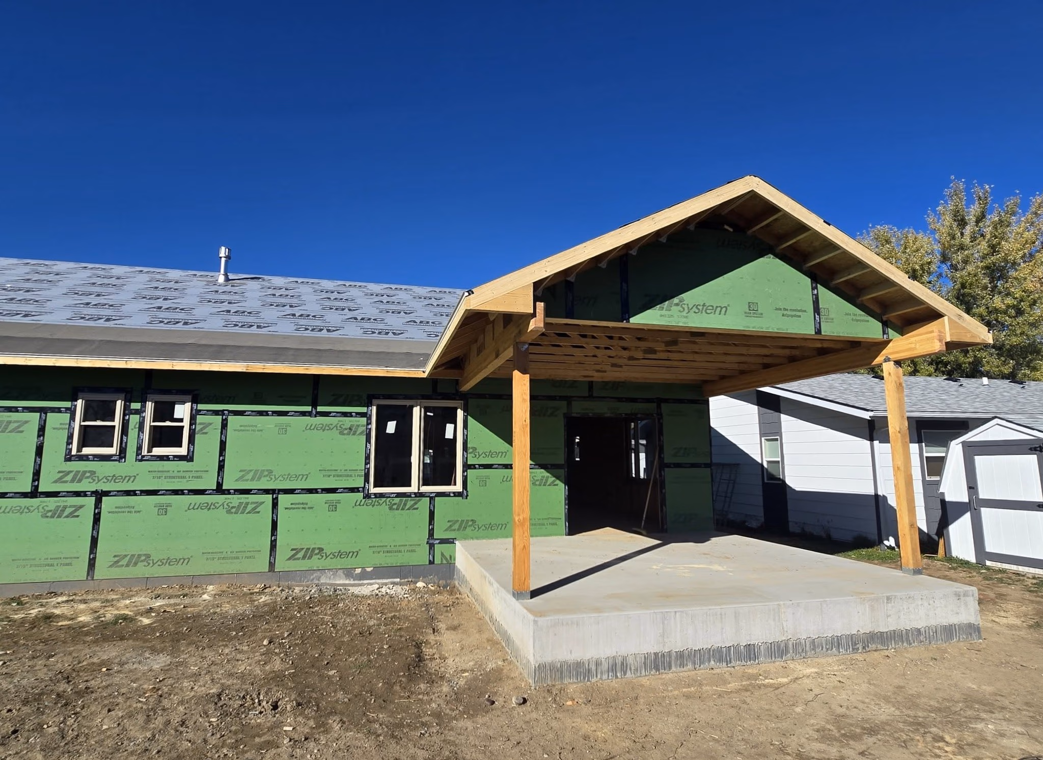 New house under construction with green ZIP System sheathing and a wooden carport frame.