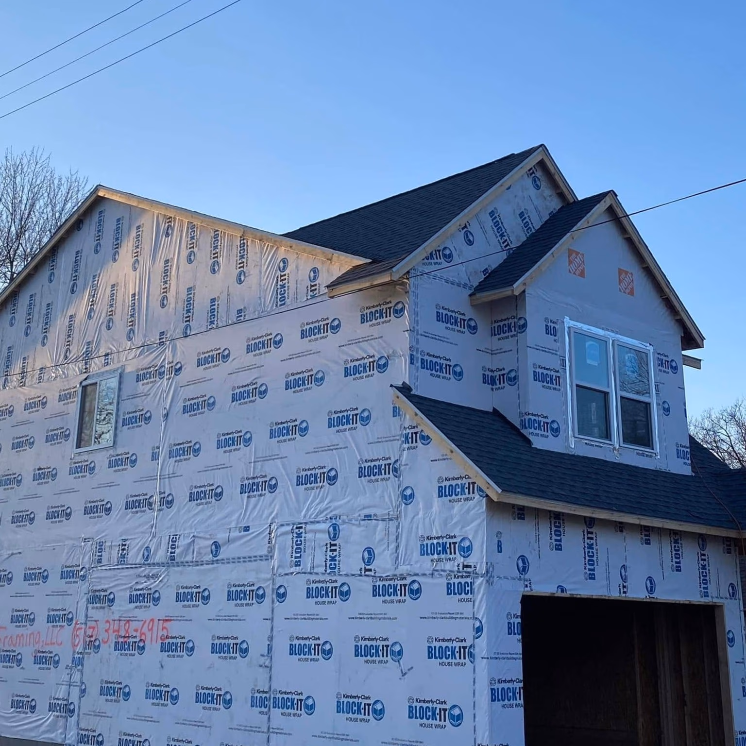 A house under construction wrapped in Kimberly-Clark BLOCK-IT house wrap with a finished shingle roof.